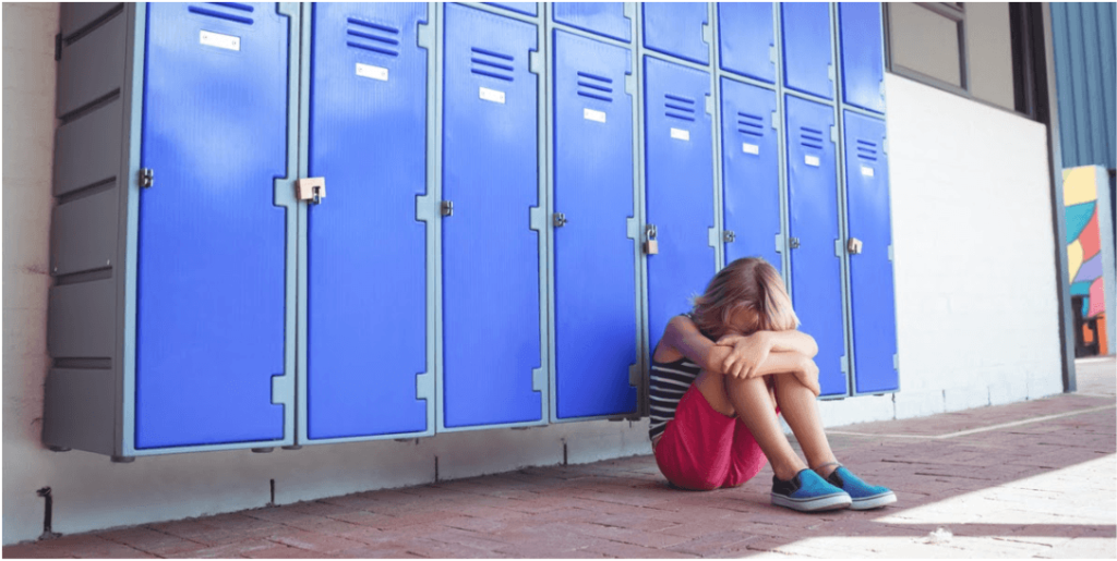 blond girl crying on the school corridor floor