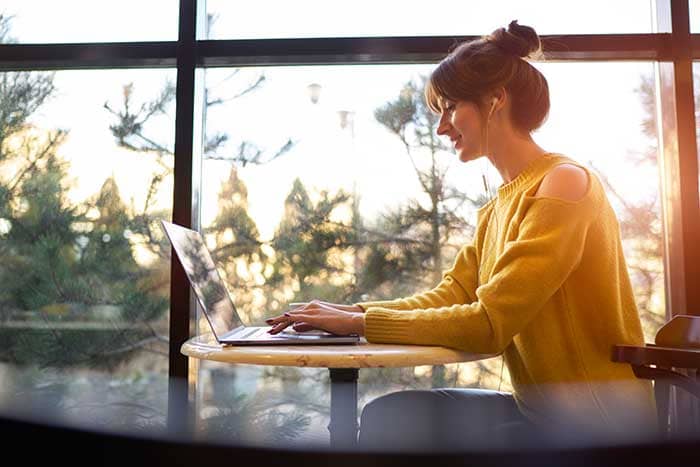 Woman in a yellow top working on a laptop