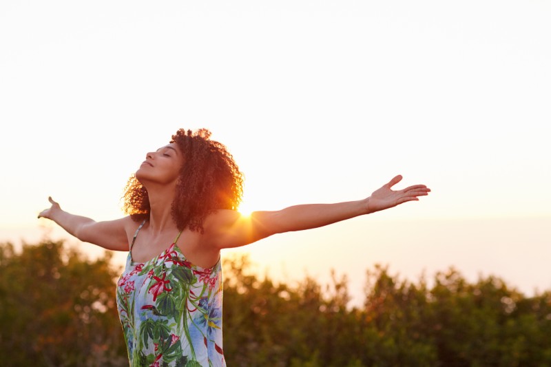 A woman outside during sunset with her arms outstretched.